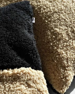 Dos almohadones sherpa CHECK by ONYX. Foto en estudio con zoom en textura sherpa suave.