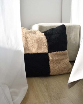 Almohadón decorativo sherpa CHECK by ONYX. Foto en ambiente sobre piso.