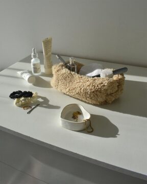 Neceser beige Sherpa fotografiado en ambiente sobre cómoda con varios productos
