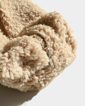 Neceser beige Sherpa fotografiado en estudio con enfoque en tela Sherpa. Estructura general liviana.