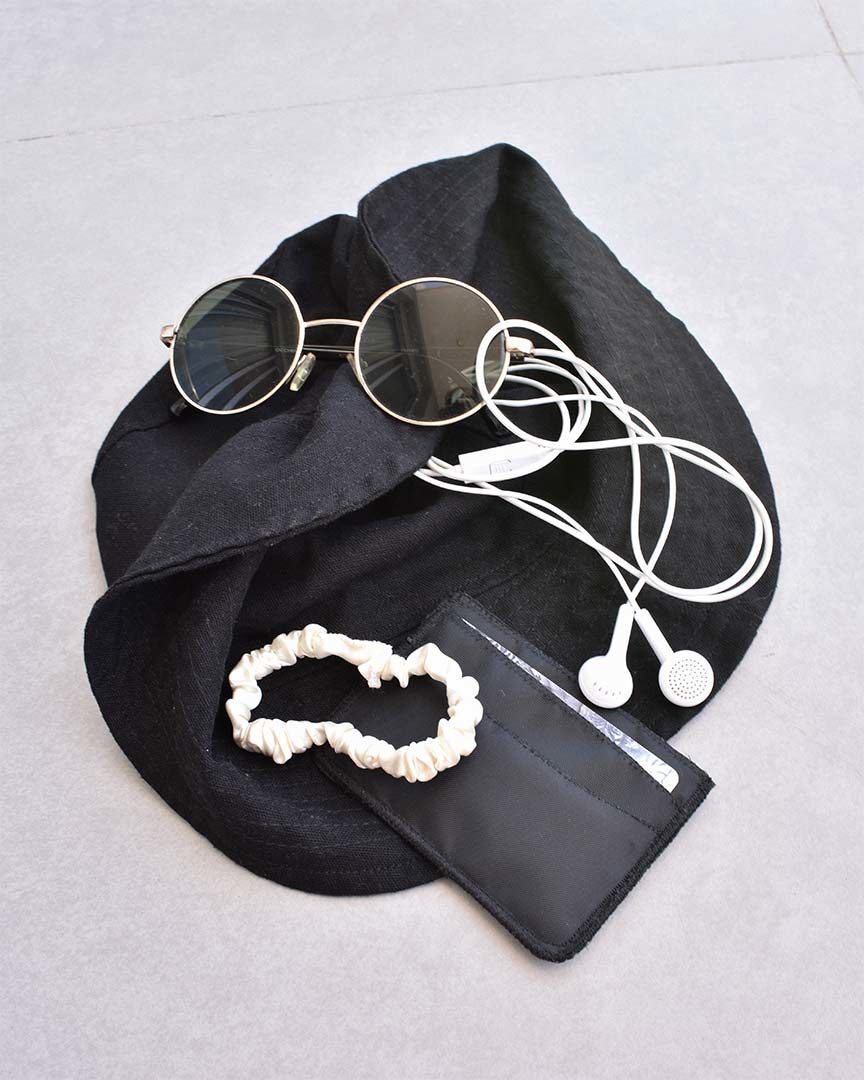Tarjetero negro Slim fotografiado con accesorios de verano.